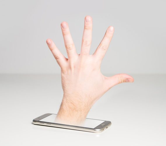 Eine Hand kommt aus einem Handy und bringt symbolisch Schadsoftware mit. Foto: Pixabay