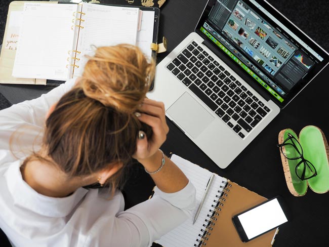 Draufsicht auf Frau, die vor Laptop sitzt und den Kopf abstützt. Bild: Pexels/energepic.com (https://www.pexels.com/de-de/foto/frau-sitzt-vor-macbook-313690/)