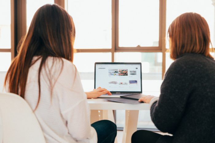 Microsoft Teams-App: Zwei Frauen sitzen gemeinsam an einem Laptop. Bild: Unsplash / KOBU Agency
