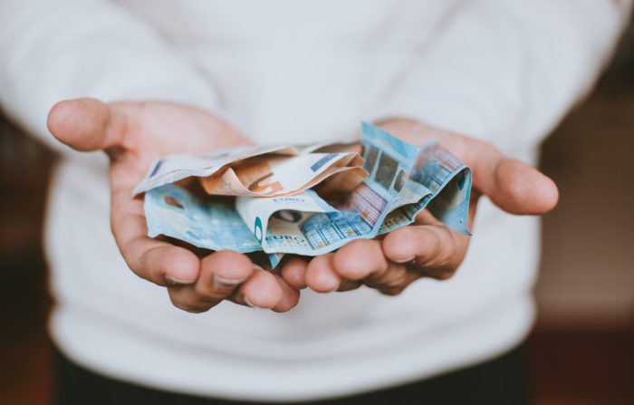 Das Bild zeigt eine Hand mit Bargeld. Bild: Unsplash/Christian Dubovan