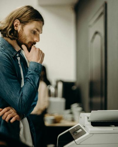 Drucker druckt nicht: Mann steht am Drucker. Bild: Pexels/cottonbro studio (https://www.pexels.com/de-de/foto/mann-mit-einem-drucker-3201783/)