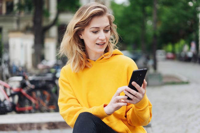Junge Frau liest E-Mails auf Ihrem Handy. Bild: stock.adobe.com/contrastwerkstatt (https://stock.adobe.com/de/images/frau-ist-in-der-stadt-unterwegs-und-tippt-eine-nachricht-auf-ihrem-handy/271461385?asset_id=271461385)