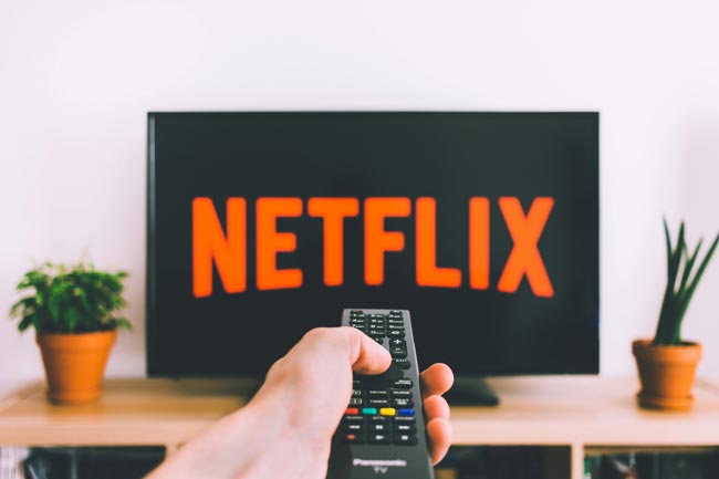 Netflix: Person hält Fernbedienung, um Netflix auf dem Fernseher zu streamen. Bild: Pexels/freestocks.org (https://www.pexels.com/de-de/foto/987586/)