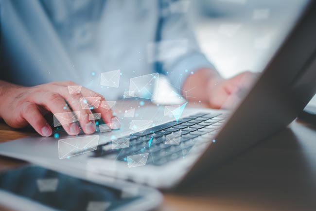 Serienbrief erstellen: männliche Person am Laptop, virtuelle Briefe „fliegen“ aus dem Rechner. Bild: stock.adobe.com/Looker_Studio (https://stock.adobe.com/de/images/business-man-working-on-laptop-computer-and-he-is-sending-email-in-modern-office-direct-marketing-digital-message-and-email-electronic-mail-and-network-connection-concept/361932816)