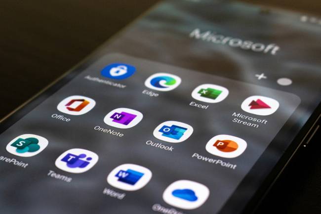 Zu sehen ist ein Handy, auf dem ein Ordner mit Microsoft-Apps aufgerufen ist. Eine Sicherheitslücke in Outlook birgt Gefahr. Bild: Unplash/Ed Hardie