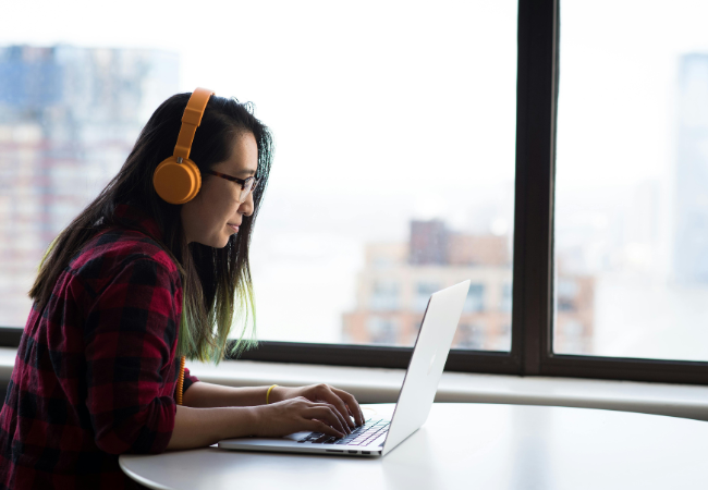 Digitale Barrierefreiheit schafft digitale und soziale Teilhabe. Zu sehen ist eine Frau mit Kopfhörern vor dem Laptop. Bild: Christina Morillo