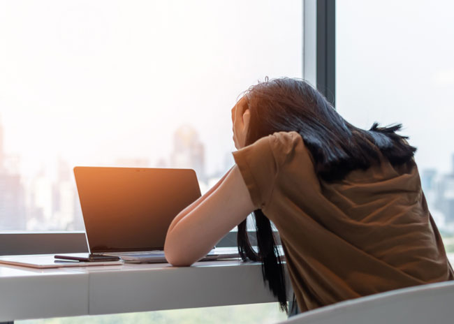 Social-Media-Betrug | Frau vor Laptop. Bild: stock.adobe.com/Chinnapong https://stock.adobe.com/de/images/panic-attack-woman-stressful-depressed-emotional-person-with-anxiety-disorder-mental-health-illness-headache-and-migraine-sitting-on-laptop-computer-desk/254906847