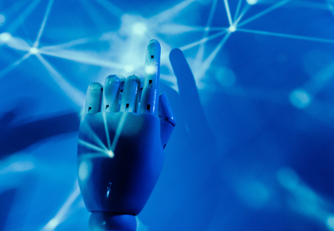 KI-Greenwashing: Informieren Sie sich vor der KI-Nutzung gründlich. Zu sehen ist eine mechanische Hand vor blauem Hintergrund, die auf Laserstrahlen zeigt. Bild: Pexels/ Tara Winstead https://www.pexels.com/de-de/foto/hand-finger-zukunft-roboter-8386437/