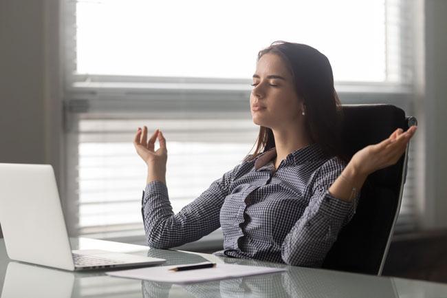 Geschäftsfrau führt Atemübungen gegen E-Mail-Angst aus. Bild: stock.adobe.com/fizkes https://stock.adobe.com/de/images/calm-female-office-employee-meditating-at-workplace/305175802