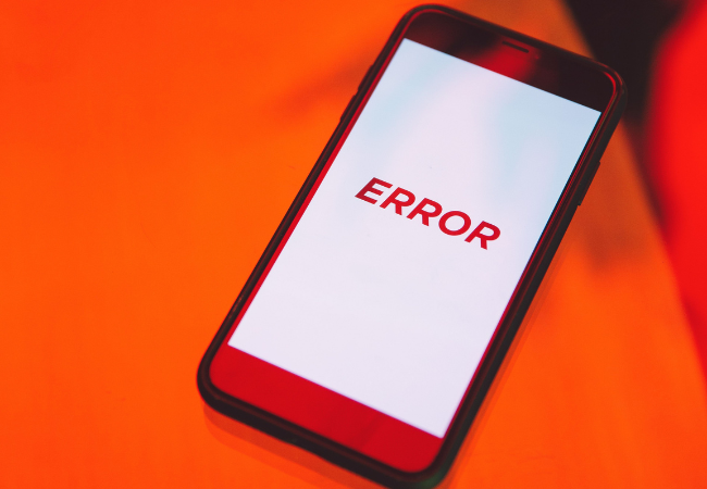 Alert Fatigue: Zu viele nicht priorisierte Alarme in der IT kosten Ressourcen. Zu sehen ist ein knallroter Hintergrund mit einem Handy, auf dem in roter Schrift Error steht. Bild: Pexels/ Polina Zimmermanhttps://www.pexels.com/de-de/foto/nahaufnahmefoto-des-schwarzen-smartphones-3747159/